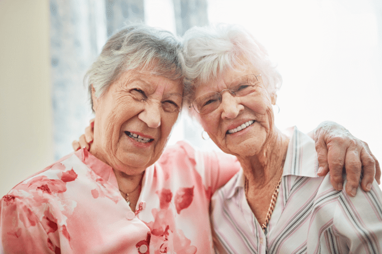 Friends, senior women and retirement home with hug or happy and fun. Pensioner, portrait and smile or confident in bonding to relax on break at old age house for wellbeing, wellness and health