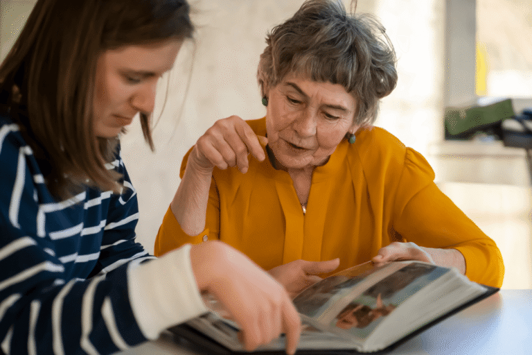 Grandmother and her young granddaughter spend time together looking at a photo album.